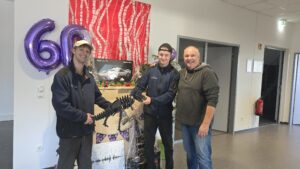 Die Auszubildenden gratulieren und überreichen einen Blechdino.